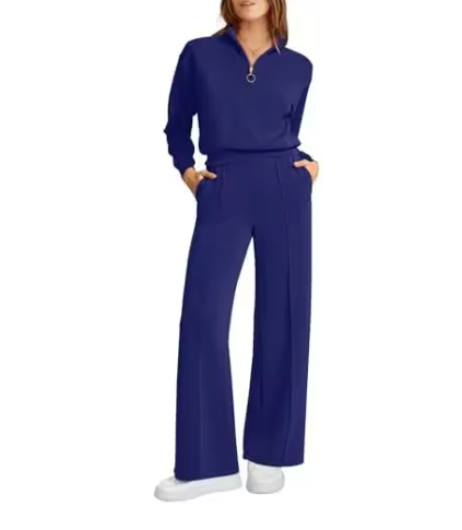 Mulher usando conjunto Royal Comfort coral: blusa meio-zip e calça wide leg de moletom premium, visual elegante e confortável com mãos nos bolsos.