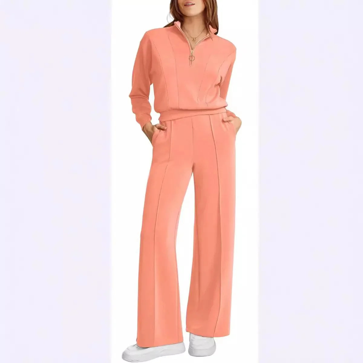 Mulher usando conjunto Royal Comfort coral: blusa meio-zip e calça wide leg de moletom premium, visual elegante e confortável com mãos nos bolsos.

